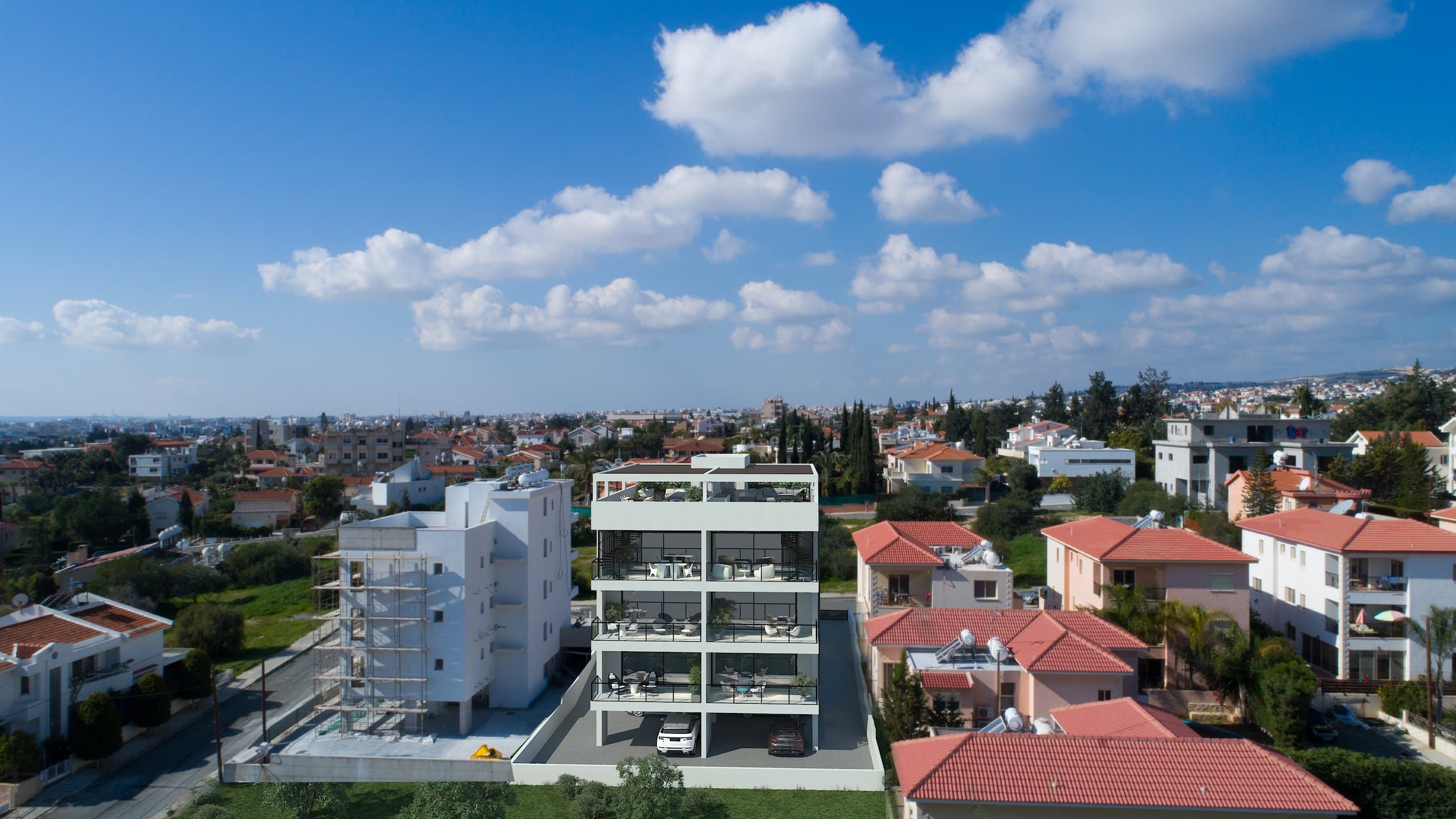 The completed Simplicity 1 residence from the air, red roofs and the sea behind